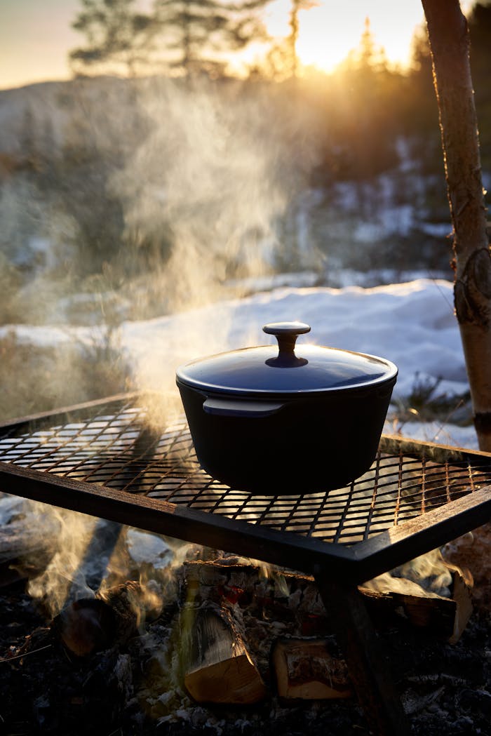 about-02 Cast iron pot steaming on a grill outdoors during sunset in winter.