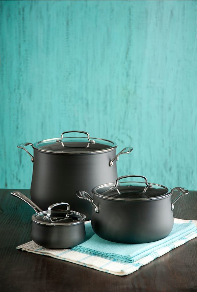 Stylish black pots and saucepan on a turquoise backdrop, perfect for kitchen decor.