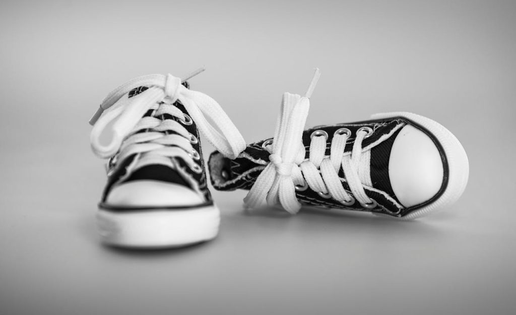 Black and white high-top sneakers with laces in a classic studio setting.